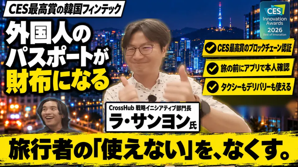 夜のソウルの街を背景に、両手の親指を立てて笑うCrossHub 戦略イニシアティブ部門長のラ・サンヨン氏と、左下で笑う聞き手の小笠原。「CES最高賞の韓国フィンテック」「外国人のパスポートが財布になる」「旅行者の「使えない」を、なくす。」の文字、CES最高賞のブロックチェーン認証・旅の前のアプリでの本人確認・タクシーやデリバリーを示す3つの札と、CES 2026 Innovation Awardsの印